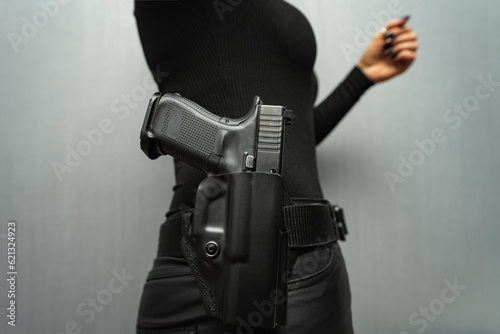 A pistol in a holster in a girl on a black jeans belt. photo