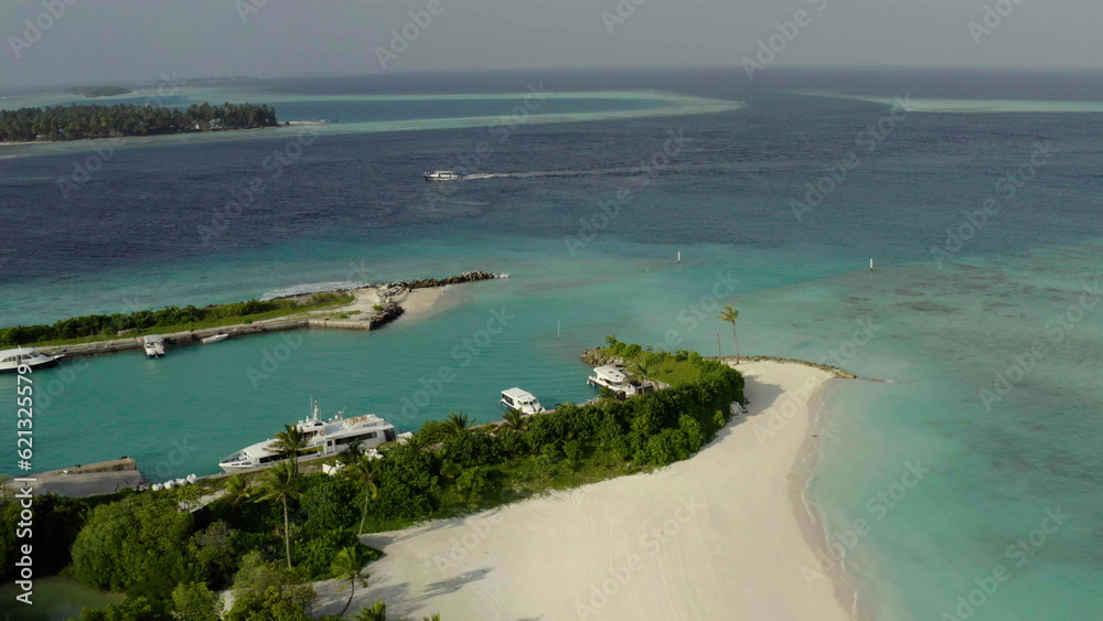 Aerial video of a drone flying over a picturesque beach with white sand and blue water, palm trees and sea waves.