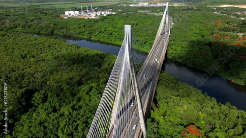 Aerial rising spin view of The Mauricio Baez cable-stayed Bridge over the river. Cars driving on the highway at sunrise. San Pedro de Macoris, Dominican Republic photo