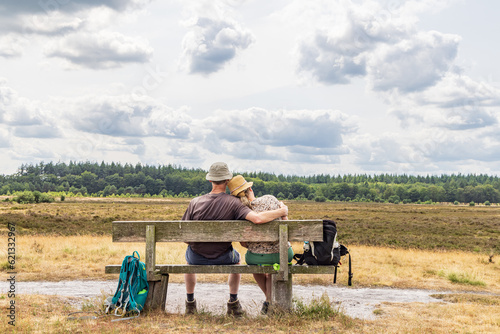 Senior couple hikers resting on wooden bench in nature park Molenveld in Exloo municipality Borger-Odoorn in Drente The Netherlands