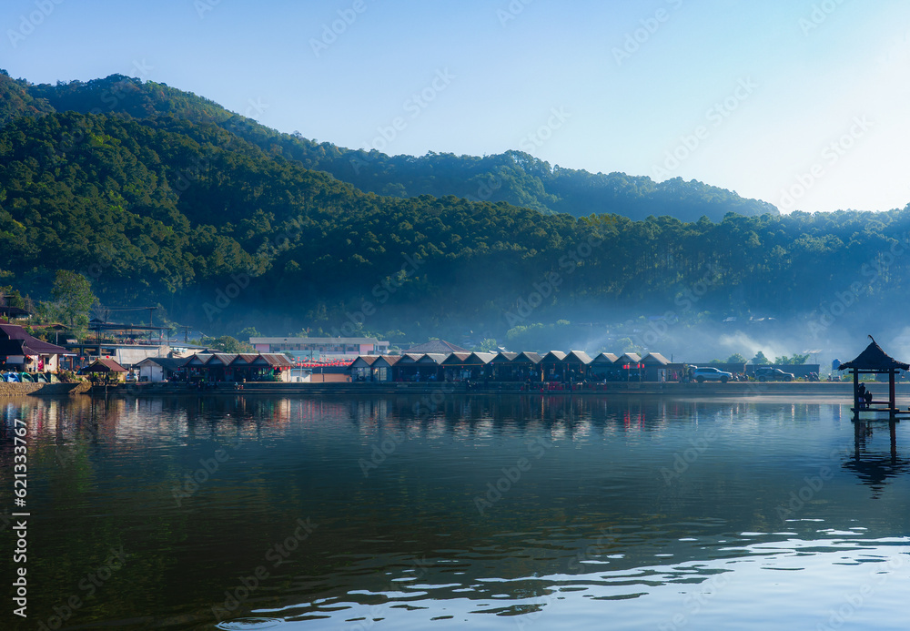 A view of a village with morning mist and surrounded by mountains.