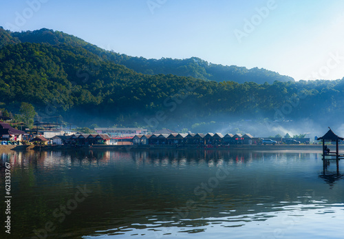 A view of a village with morning mist and surrounded by mountains.