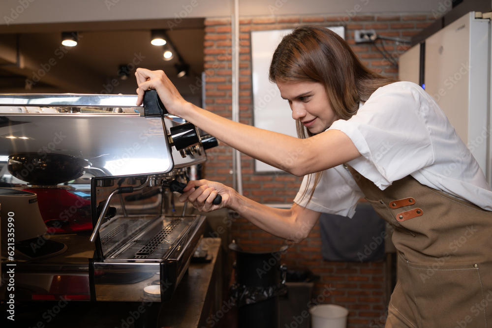 Young female barista preparing coffee in cafe. Female barista using coffee machine.