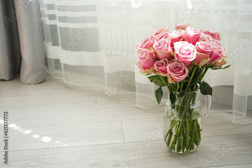 Bouquet of pink roses in a glass decanter, space for text. Beautiful, bright floral background.