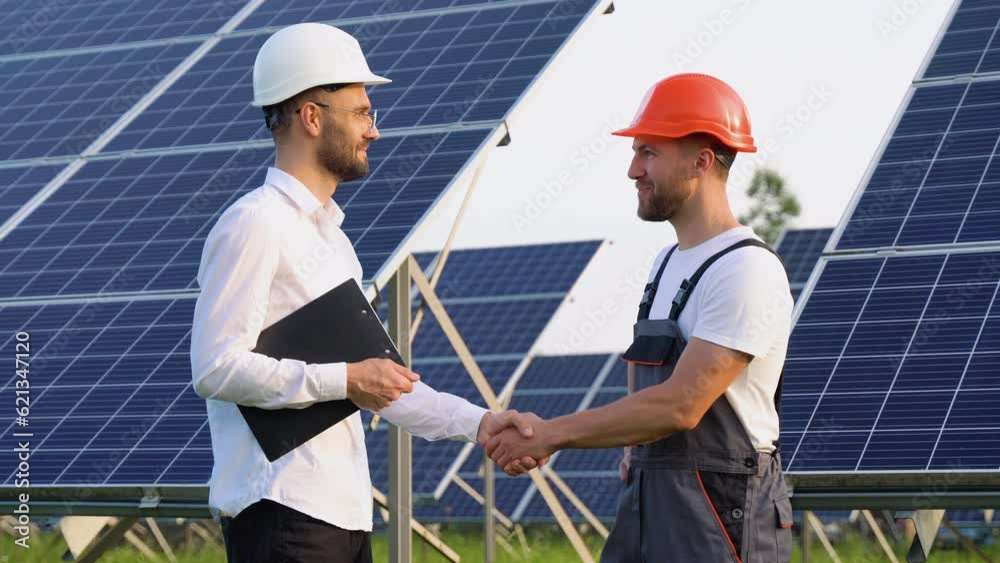 Two engineers boss and subordinate shaking hands after discussion on background of photovoltaic solar panels Two engineers boss and subordinate shaking hands after discussion on background of photovoltaic solar panels