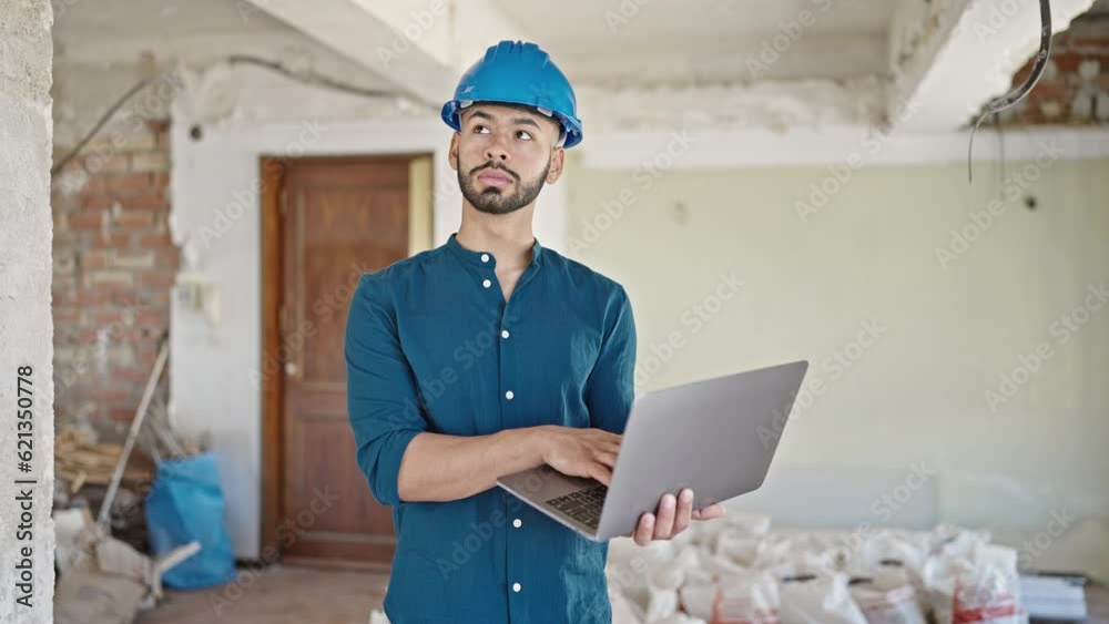 Young hispanic man architect wearing hardhat using laptop at construction site Young hispanic man architect wearing hardhat using laptop at construction site