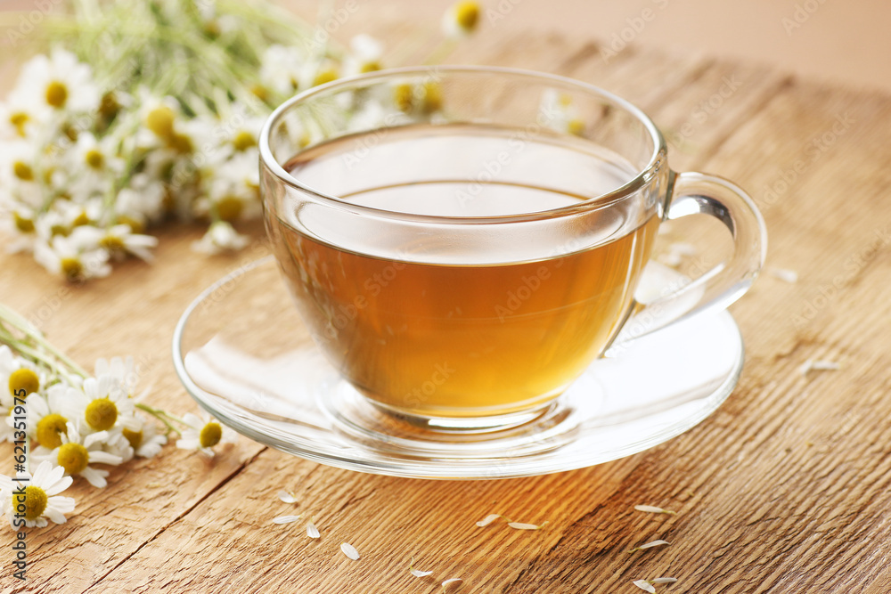 Chamomile herbal tea in a glass cup with flowers on wooden rustic background, closeup, winter cold healing drink, natural medicine and naturopathy concept Chamomile herbal tea in a glass cup with flowers on wooden rustic background, closeup, winter cold healing drink, natural medicine and naturopathy concept