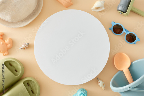 The idea of a beachside getaway for children during the summer. Top view of footwear  sunglasses  beach toys  seashells  panama hat on pastel beige background with blank circle for advert or text