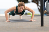 Adult athletic woman with no make up doing push ups outdoors