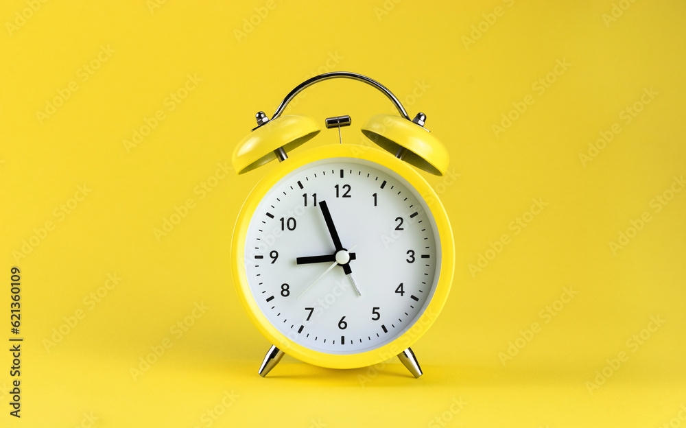 Yellow alarm clock on a colored yellow background. Monochrome. Minimalism. Concept of time, planning. Yellow alarm clock on a colored yellow background. Monochrome. Minimalism. Concept of time, planning.