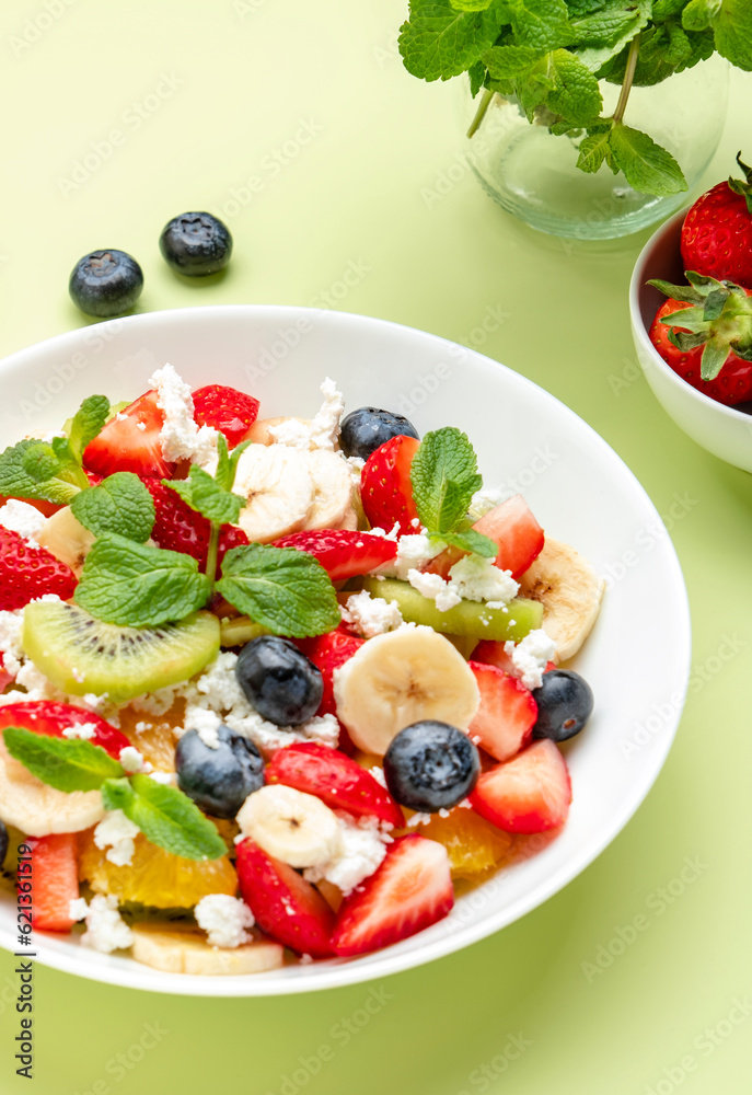 Summer fruit and berry salad with feta cheese, fresh strawberries, blueberries, banana, kiwi, orange and mint, green background, top view Summer fruit and berry salad with feta cheese, fresh strawberries, blueberries, banana, kiwi, orange and mint, green background, top view
