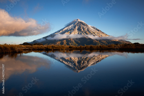 Mount Egmont, also called Mt Taranaki on the north Island of New Zealand during sunset with a beautiful reflection in the water of a little lake photo