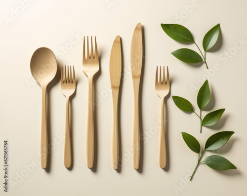 Wooden decomposable forks  spoons and knives on a light surface with green leaves.conceptual ecology and recycling problem.flat lay. Generative AI