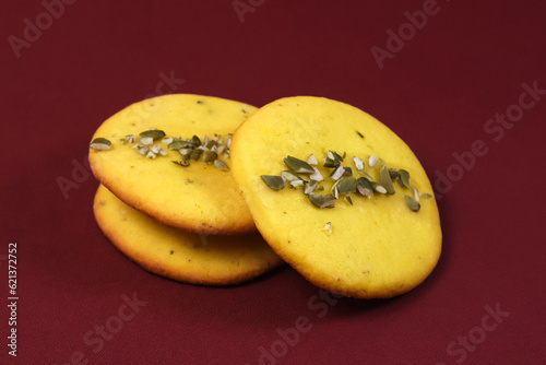 Lemon cookies with pumpkin seeds on a burgundy table. Close-up 