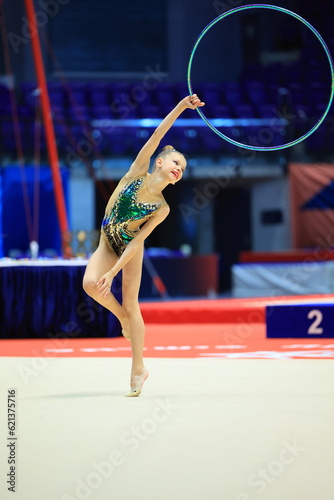 girl gymnast performs an exercise with a hoop