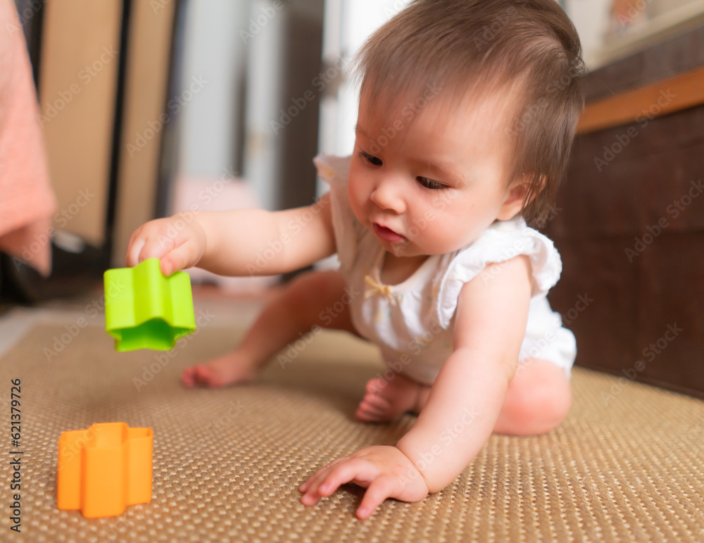 lifestyle home portrait of adorable and beautiful Asian Caucasian mixed baby girl playing on the floor with color blocks excited and happy in childhood concept