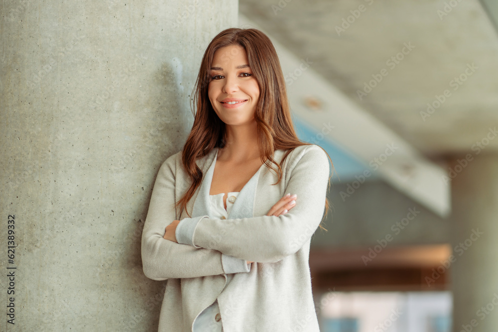 Portrait of positive smiling woman with crossed arms standing in modern office Portrait of positive smiling woman with crossed arms standing in modern office