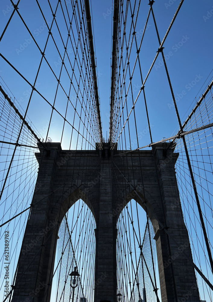Obraz premium Cables leading up to a tower on the Brooklyn Bridge against a blue sky