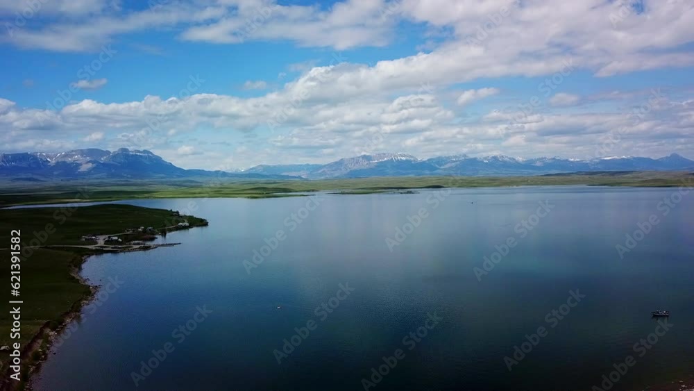 Aerial Shot Of Lake Near Mountain Ranges Against Sky, Drone Ascending Backward Over Vehicles At Lakeside - Billings, Montana Aerial Shot Of Lake Near Mountain Ranges Against Sky, Drone Ascending Backward Over Vehicles At Lakeside - Billings, Montana