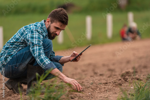 Fototapeta Male farmer plantation checking quality by tablet agriculture modern technology concept smart farming agronomist checking soil quality on the field