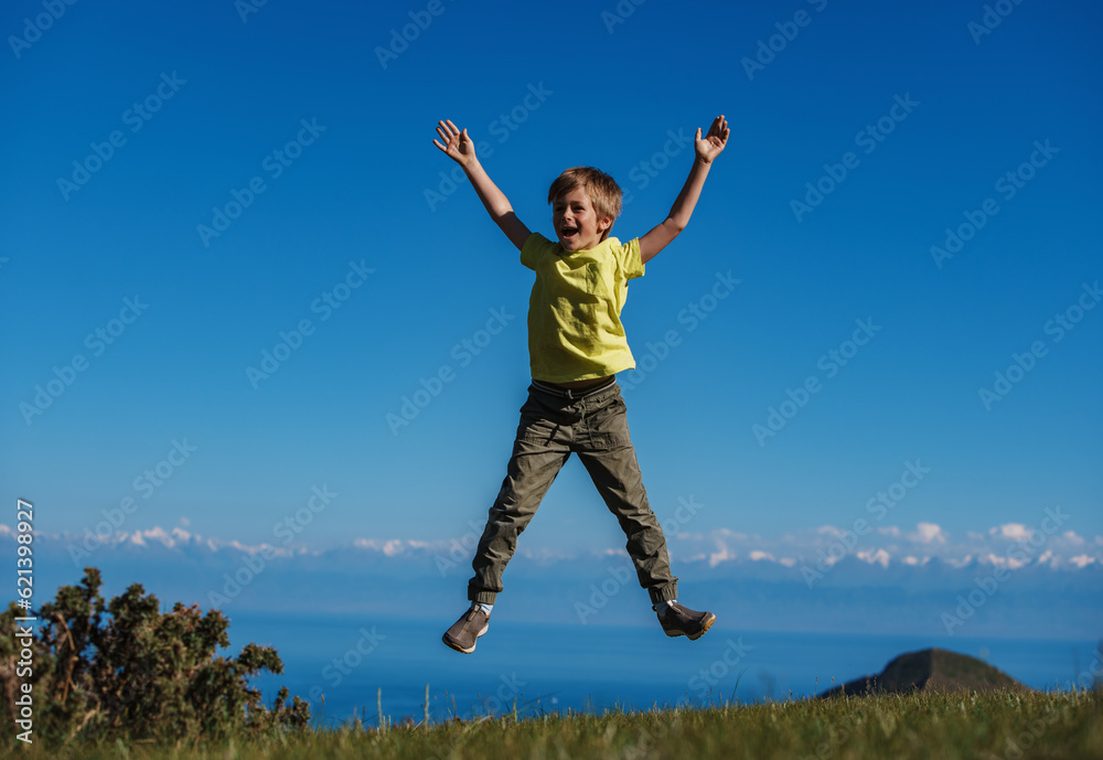 Happy boy jumps in the mountains on lake background Happy boy jumps in the mountains on lake background