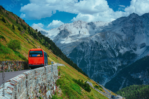 Red touristic bus riding at Swiss Alps mountains in summer