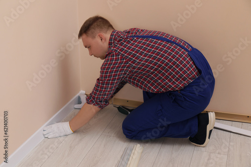 Man installing plinth on laminated floor in room © New Africa