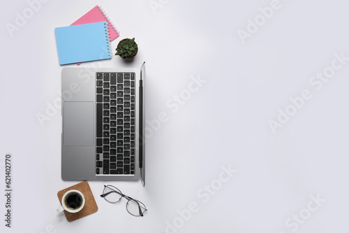 Modern laptop, notebooks and cup of coffee on white table, flat lay. Space for text