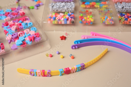 Handmade jewelry kit for kids. Colorful beads, and wristbands on beige background