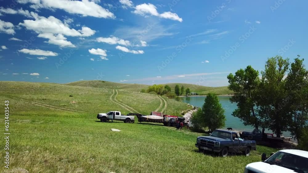 Aerial: Drone Flying Backward Over Vehicles With People And Dogs At Lakeside Against Blue Sky During Sunny Day - Billings, Montana Aerial: Drone Flying Backward Over Vehicles With People And Dogs At Lakeside Against Blue Sky During Sunny Day - Billings, Montana