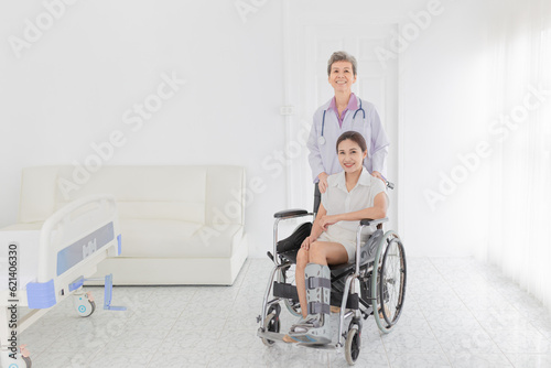 Asian patient sitting on wheelchair, patient wear air cast walking boot, doctor and patient talk about symptoms and treatment plan, rehabilitation activity