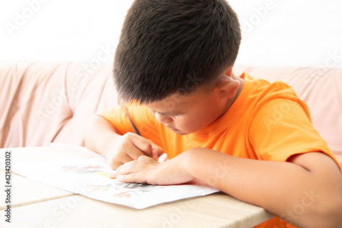 Little schoolboy writing in notebook at lesson. A boy doing his homework in the room.
