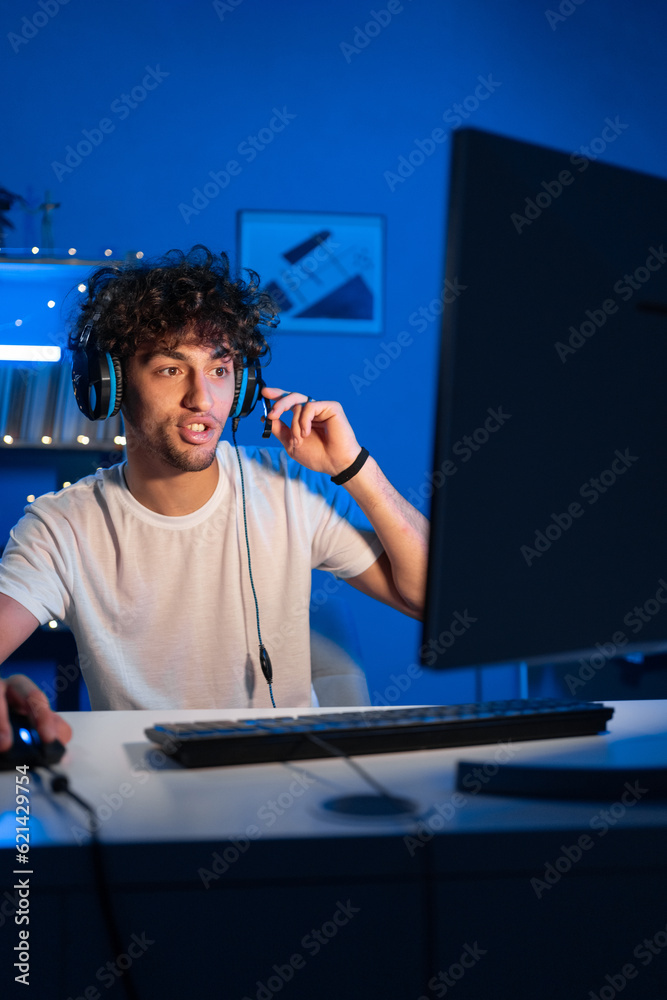 Positive arabic guy gamer streams game on computer and looks smiling at the camera. Smiling gamer playing video games Positive arabic guy gamer streams game on computer and looks smiling at the camera. Smiling gamer playing video games