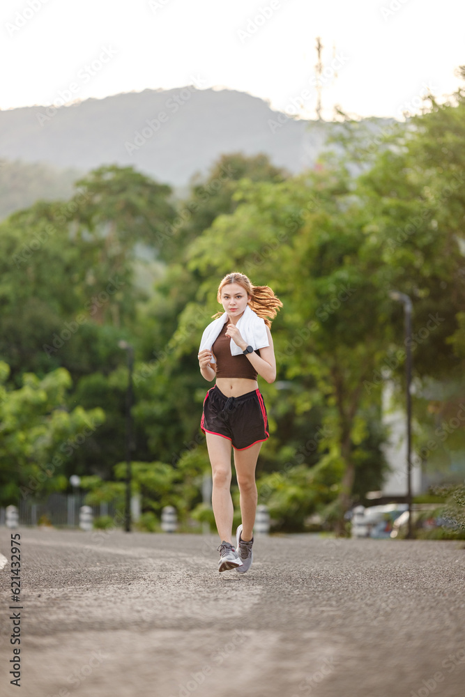 Healthy Asian woman is jogging running outdoor. Sport girl running. Female exercising at outdoor park. Sunset or Sunrise. Healthy Asian woman is jogging running outdoor. Sport girl running. Female exercising at outdoor park. Sunset or Sunrise.