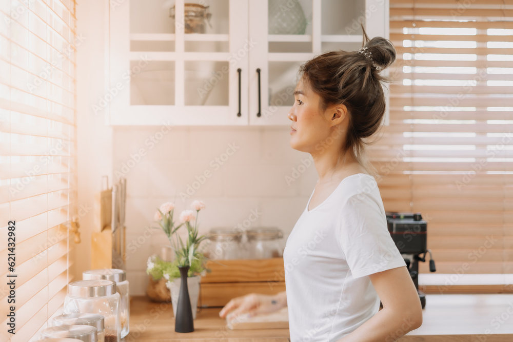 Asian woman looking out the window from white warm kitchen. Asian woman looking out the window from white warm kitchen.