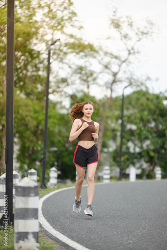 Healthy Asian woman is jogging running outdoor. Sport girl running. Female exercising at outdoor park. Sunset or Sunrise. © Treerat