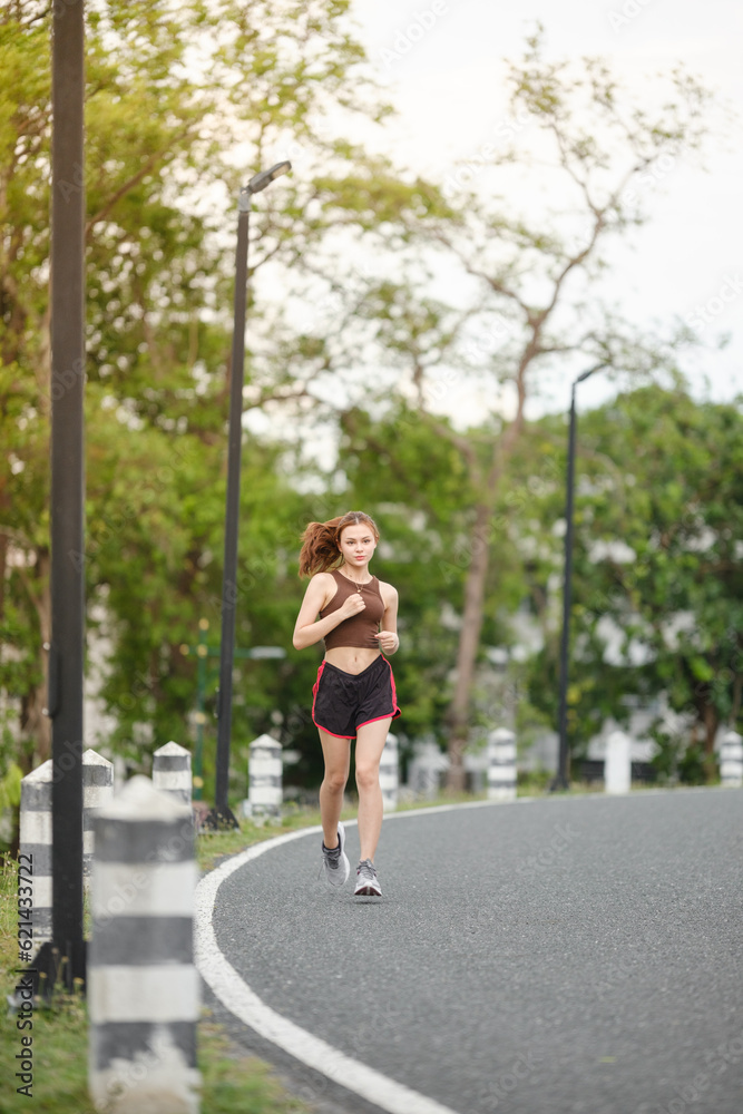Healthy Asian woman is jogging running outdoor. Sport girl running. Female exercising at outdoor park. Sunset or Sunrise. Healthy Asian woman is jogging running outdoor. Sport girl running. Female exercising at outdoor park. Sunset or Sunrise.