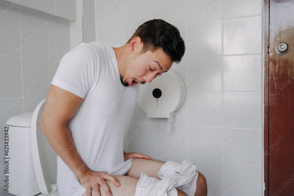 Funny face asian man pushing poop in the toilet as he has constipation