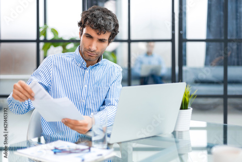 Entrepreneur opening an envelope in a desktop at office. Collegue is on the background. photo