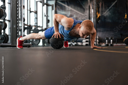 Fit man doing push ups on medicine ball at the gym.