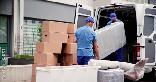 Bild auf Leinwand Male Workers In Blue Uniform Unloading Furniture