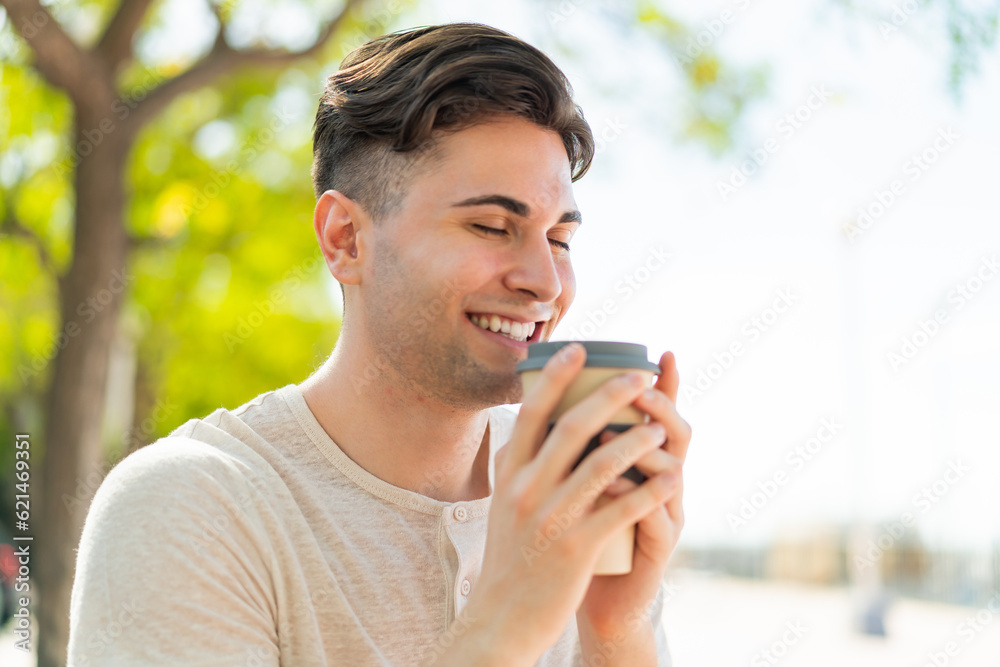 Young handsome man holding a take away coffee with happy expression Young handsome man holding a take away coffee with happy expression