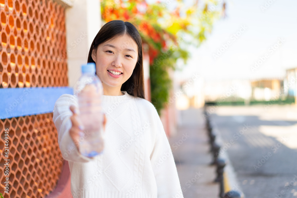 Pretty Chinese woman with a bottle of water at outdoors with happy expression Pretty Chinese woman with a bottle of water at outdoors with happy expression