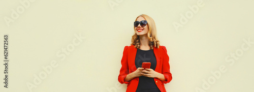 Beautiful smiling elegant lady woman with smartphone wearing red business blazer on white background