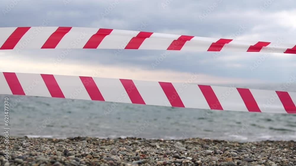 Red white warning tape barrier ribbon swinging in the wind across exotic sea beach background without people. No entry Red White caution tape. No holiday concept, delayed travel, no summer plans Red white warning tape barrier ribbon swinging in the wind across exotic sea beach background without people. No entry Red White caution tape. No holiday concept, delayed travel, no summer plans