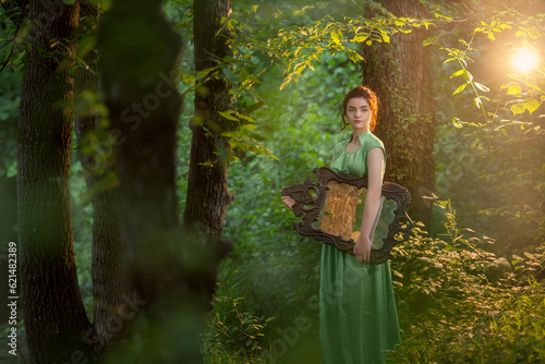Quadro em tela girl r in a green long dress stands in the forest with an antique mirror