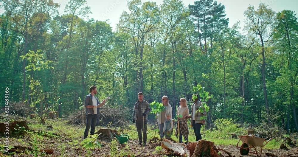 Multicultural team of volunteers divides tasks to restore state of environment. Group of young people is engaged in ecological restoration. Adult male volunteer uses digital tablet for work. Multicultural team of volunteers divides tasks to restore state of environment. Group of young people is engaged in ecological restoration. Adult male volunteer uses digital tablet for work.