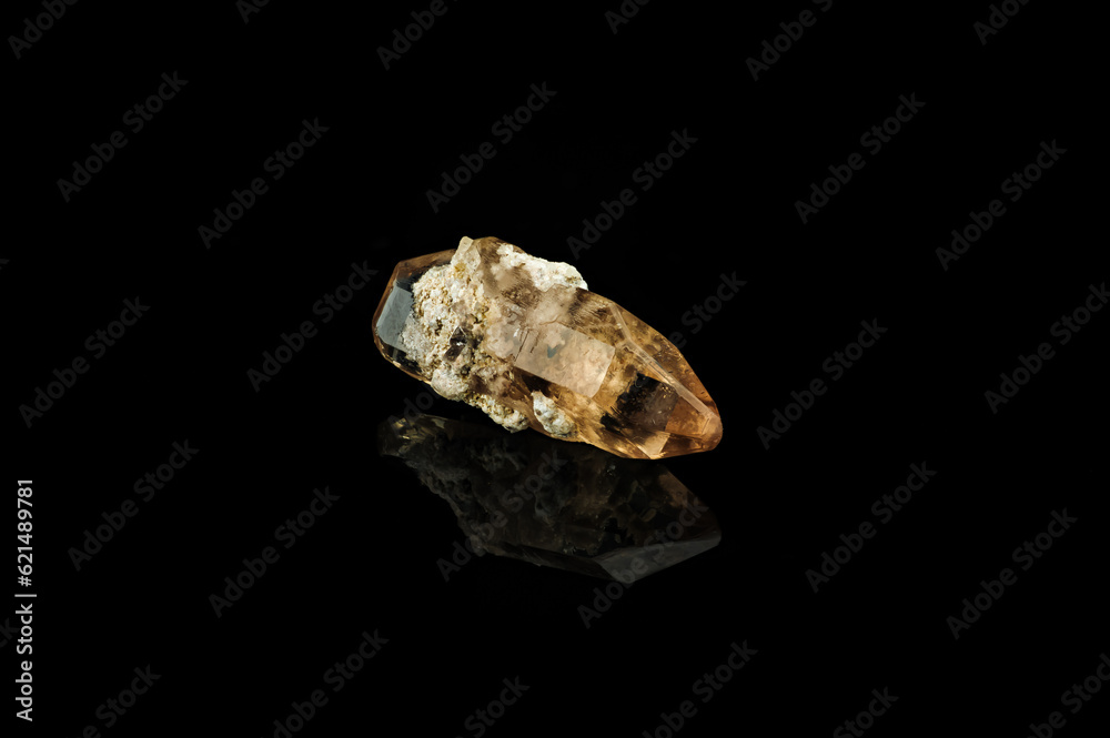 imperial topaz isolated on black background. macro detail close-up rough raw unpolished semi-precious gemstone.