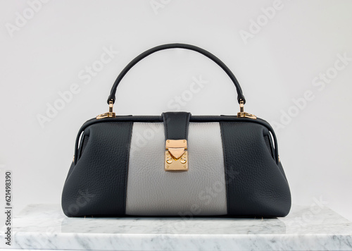 Luxury women 's bag. Luxury grey and black leather handbag on white background, on marble floor. A elegant bag with a gold accessories. Fashionable trendy 