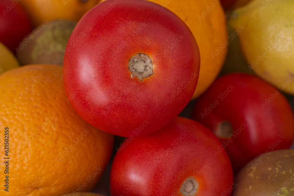 
Fresh tomato accompanied by other tomatoes and fresh fruits, oranges, lemons and pears. Tomato focused in the foreground with the background out of focus, diffuse photography. Still life of fruits an